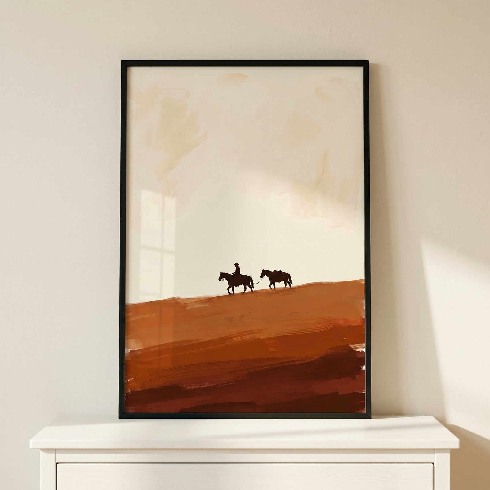 Framed earthy tone lone cowboy wall art with silhouettes of a rider leading a horse across a desert landscape.