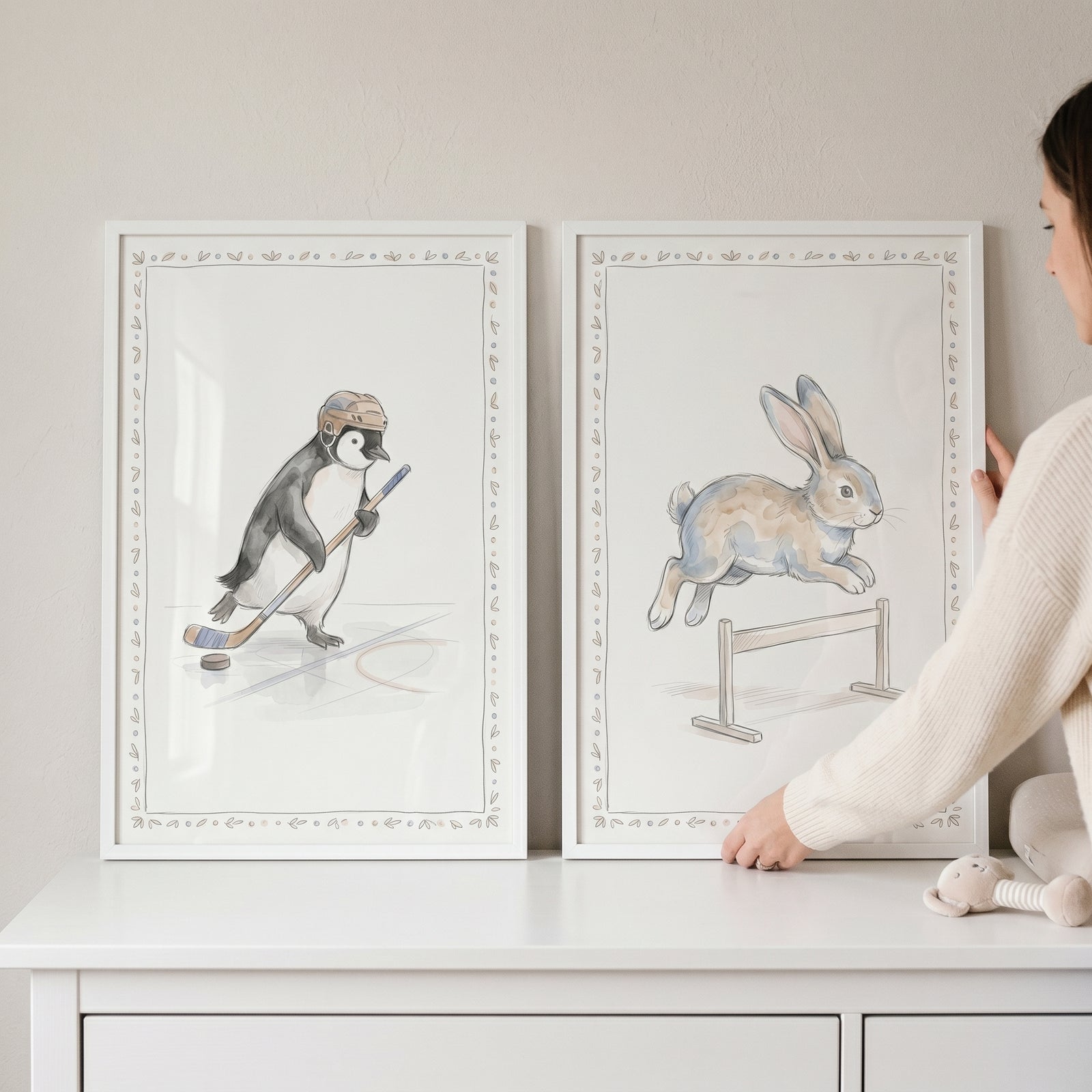 Earthy watercolor active animals wall art set of 2 featuring a penguin playing hockey and a rabbit jumping a hurdle.
