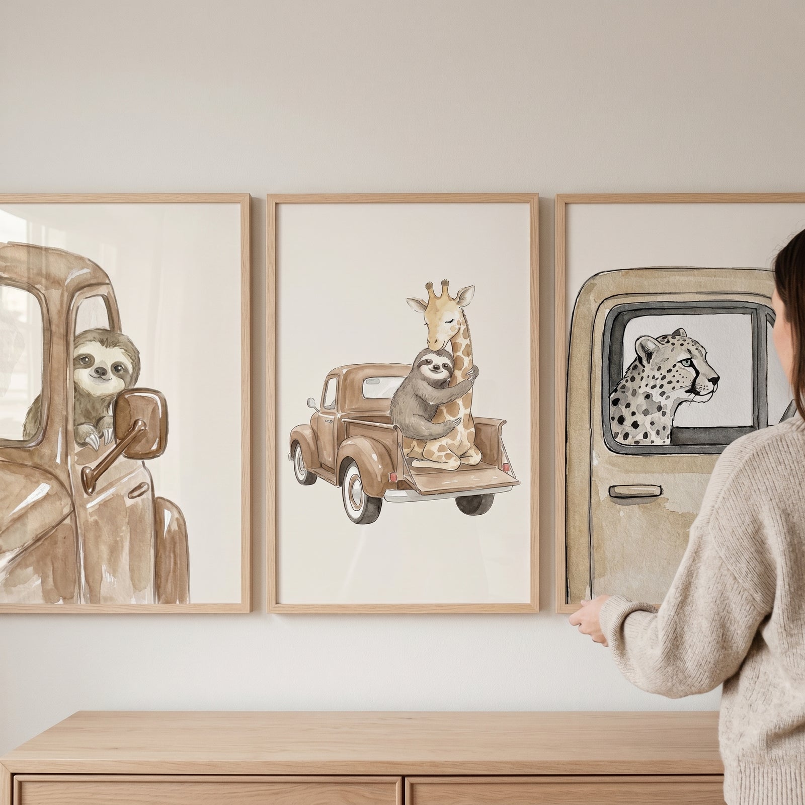 Earthy watercolor safari truck wall art set of 3 featuring a sloth, giraffe, and cheetah above a wooden dresser.