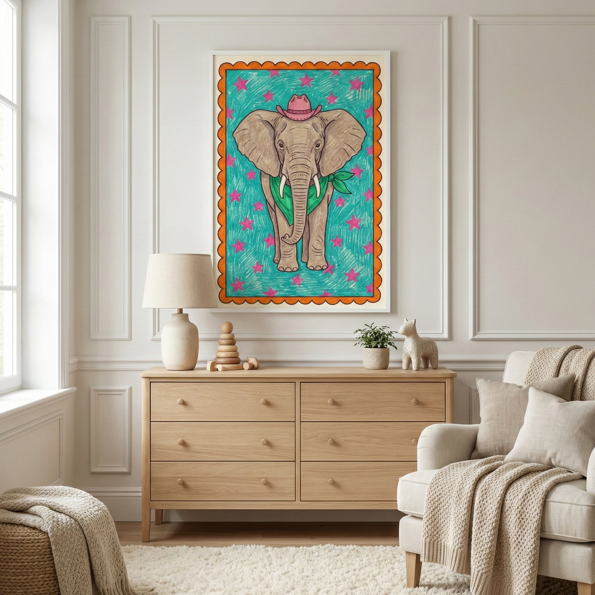 A framed illustration of an elephant wearing a pink cowboy hat and a green bandana hangs above a modern wooden dresser in a bright, neutral-toned room. The space is accented by a cream-colored armchair with textured blankets, a soft rug, and a large window.