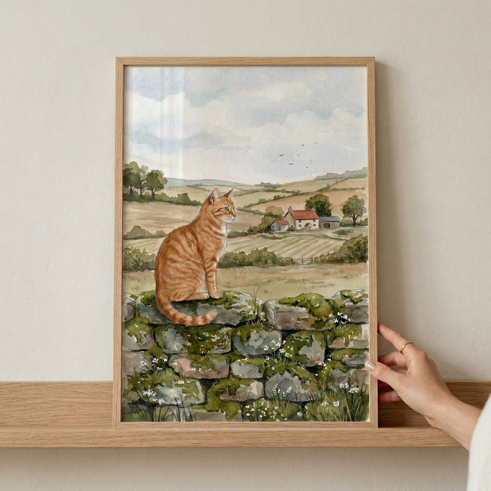 A watercolor illustration of a ginger tabby cat sitting atop a mossy stone wall. In the background, a picturesque countryside unfolds with rolling green hills, a small farmhouse with red roofs, and scattered trees. The sky is a pale blue with soft clouds and a few distant birds. The artwork is characterized by its gentle brushstrokes and a warm, natural color palette, evoking a peaceful rural setting.