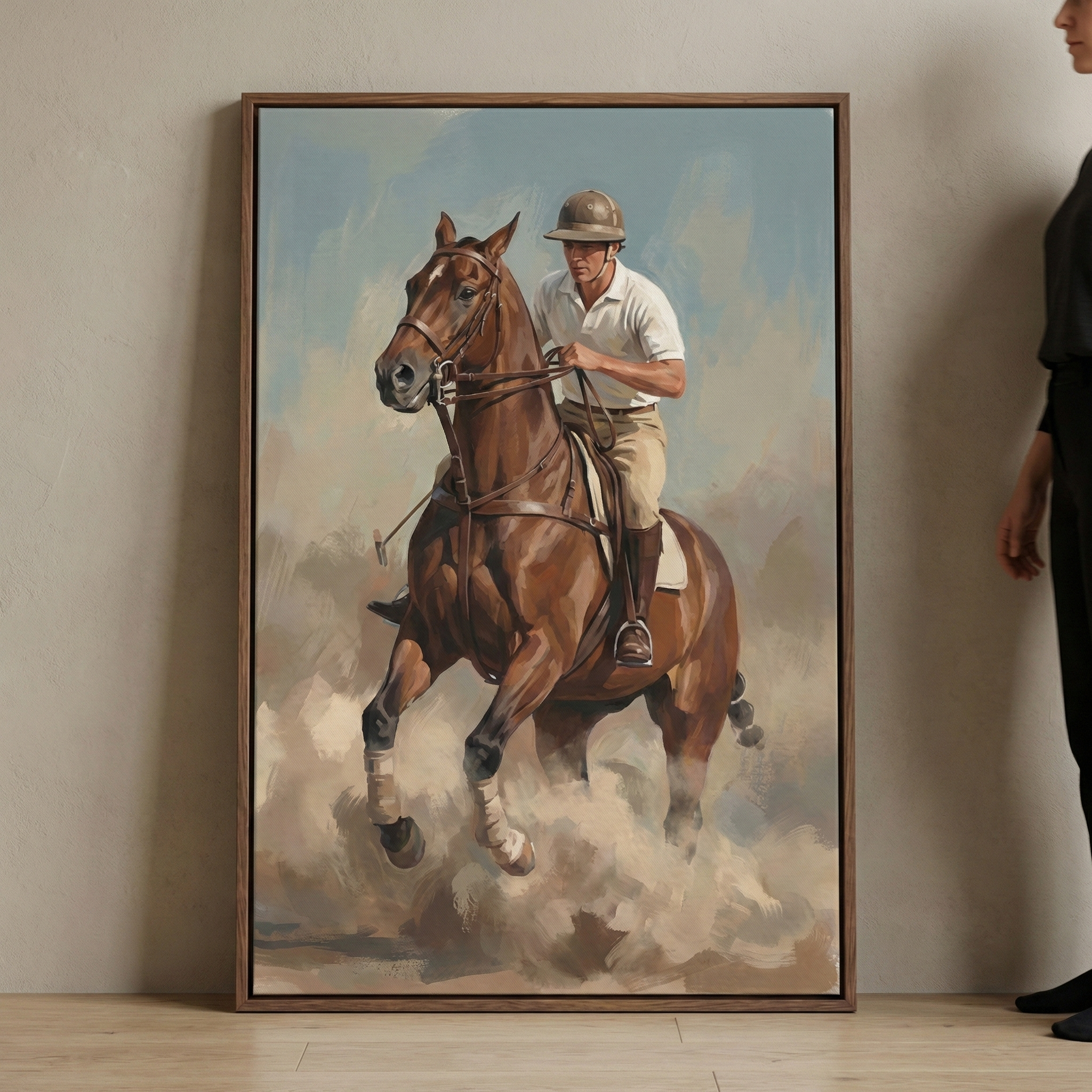 A vertical framed artwork leaning against a neutral-colored wall, depicting a person in riding attire on a brown horse galloping through dust. The rider wears a white collared shirt, tan pants, and a protective helmet. The image features visible brushstrokes and a muted color palette of blue, brown, and cream. A portion of a person standing beside the frame is visible on the right side.