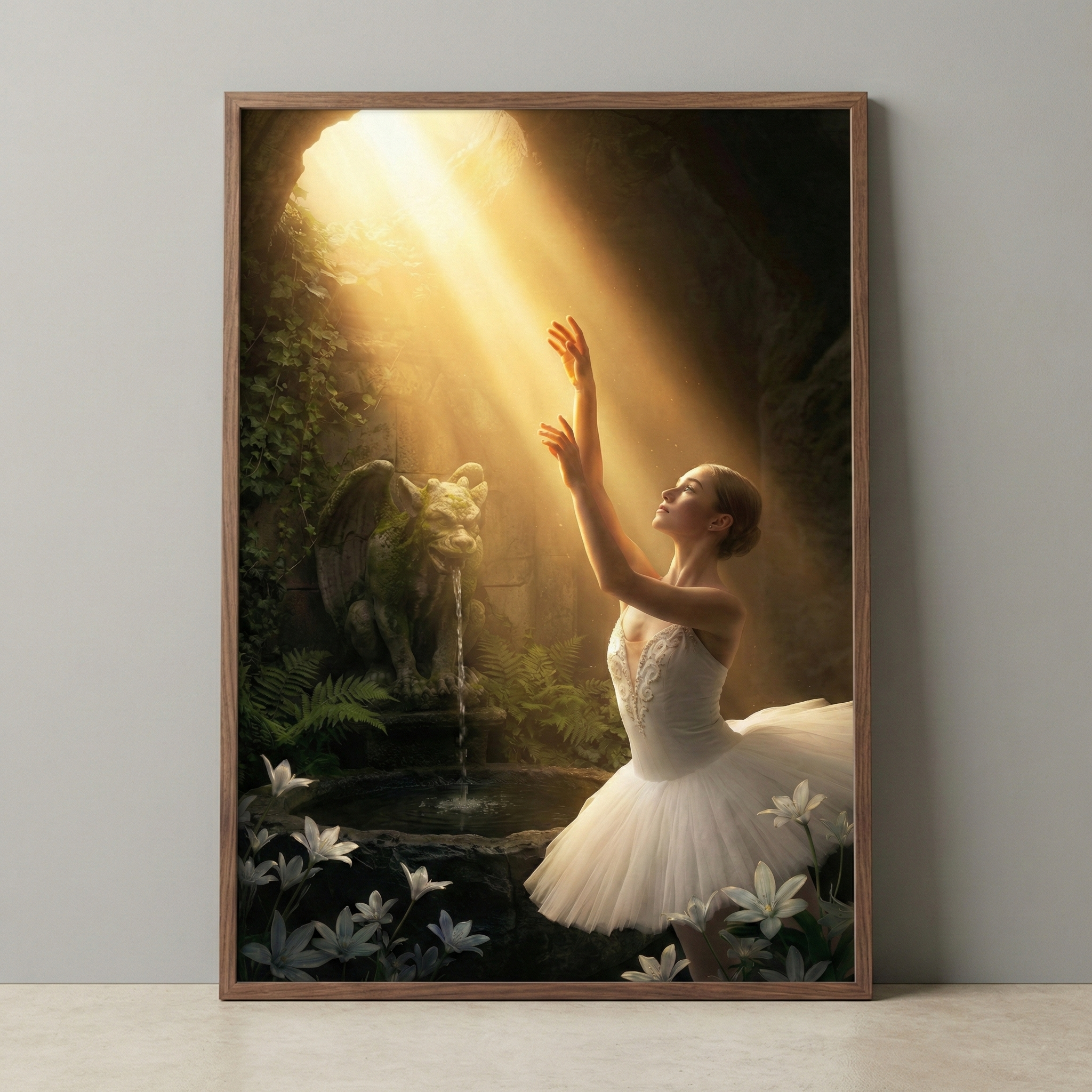 A vertical wooden-framed digital art piece depicts a ballerina in a white tutu in a sun-drenched grotto. Her arms reach toward a bright beam of golden light streaming from an opening above. To her left, a stone gargoyle statue sits atop a fountain, water trickling into a pool. The cave is lush with green ferns and mossy walls. In the foreground, white lilies bloom. The piece is displayed on a grey wall above a light-colored floor.