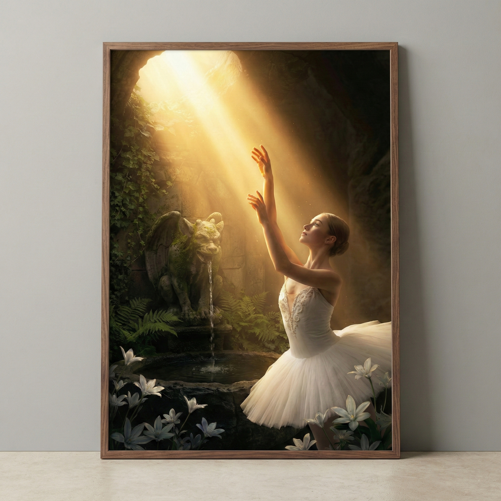 A vertical wooden-framed digital art piece depicts a ballerina in a white tutu in a sun-drenched grotto. Her arms reach toward a bright beam of golden light streaming from an opening above. To her left, a stone gargoyle statue sits atop a fountain, water trickling into a pool. The cave is lush with green ferns and mossy walls. In the foreground, white lilies bloom. The piece is displayed on a grey wall above a light-colored floor.