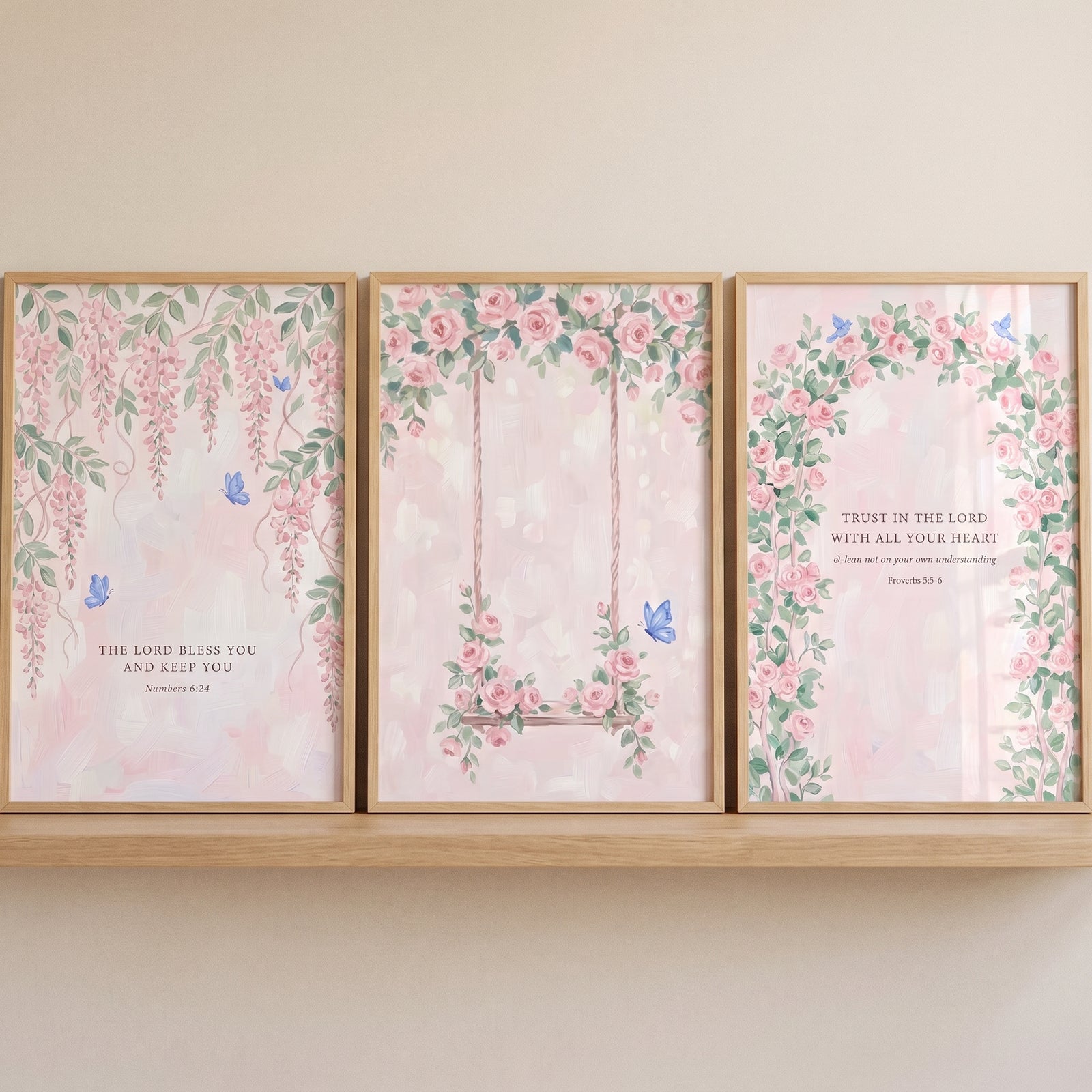 Ethereal blush botanical garden artwork set of 3 with pink flowers, blue butterflies, and scripture on a wood shelf.