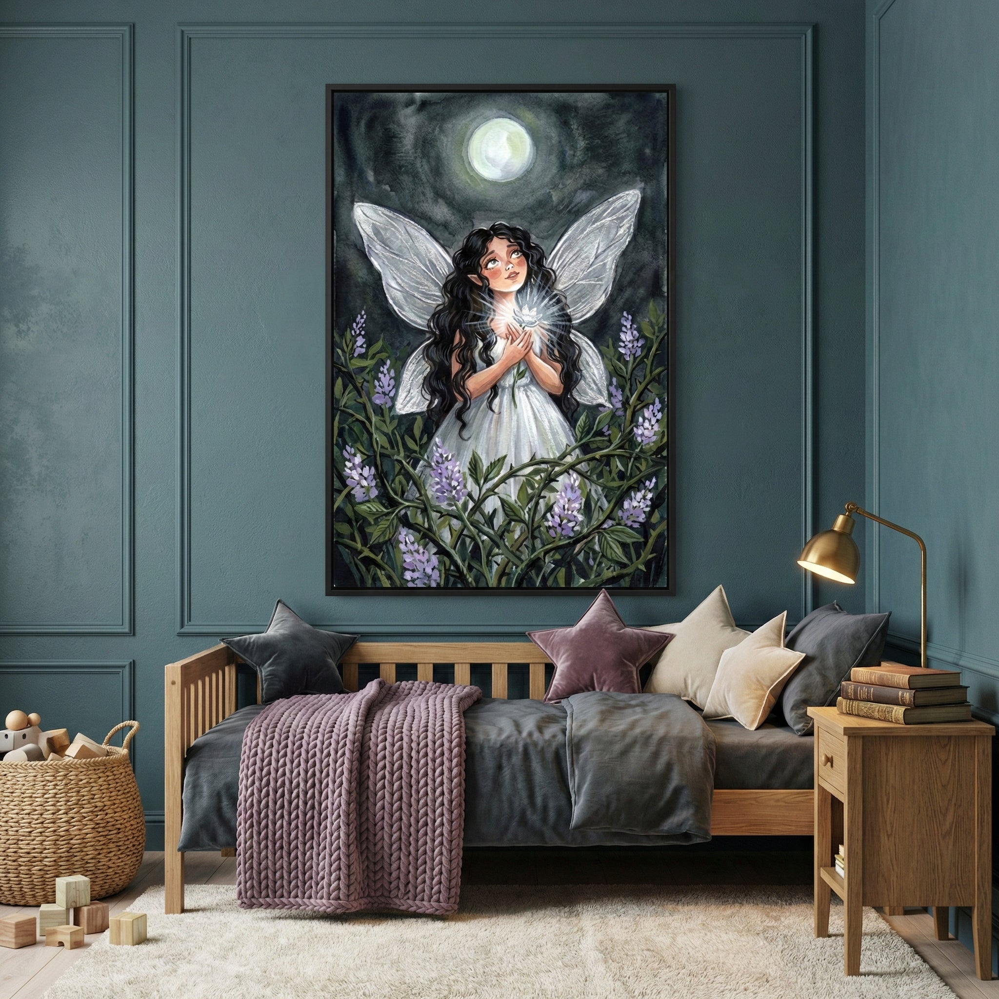 A cozy child's bedroom features teal walls and a wooden daybed. Centered above the bed is a large vertical framed illustration of a young girl with long dark wavy hair and large white wings. She wears a simple white dress and stands in a garden of purple flowers, holding a glowing light beneath a full moon in a dark night sky. The daybed is styled with a grey duvet, a textured purple throw, and several decorative pillows, including two star-shaped ones in grey and dusty rose. To the left, a woven basket hol