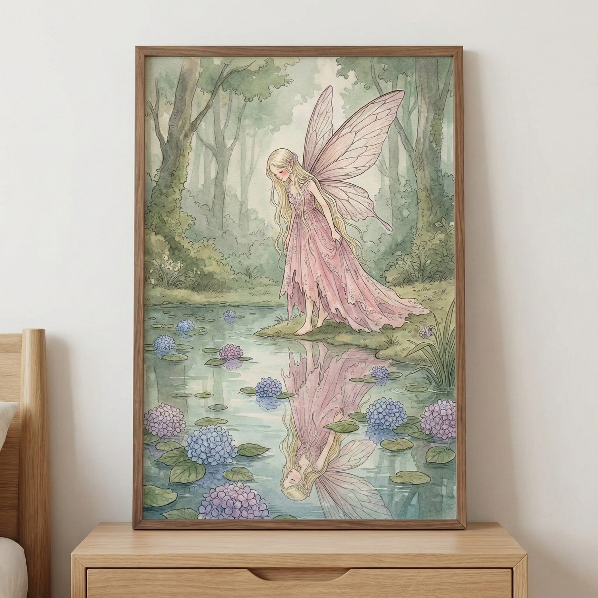 A framed illustration of a gentle fairy with long blonde hair and soft pink wings stands barefoot at the edge of a quiet forest pond, gazing at her reflection in the water. Hydrangea blossoms in shades of lavender and blue float among lily pads, and the dreamy woodland scene is styled on a light wood dresser to create a whimsical and serene bedroom accent.