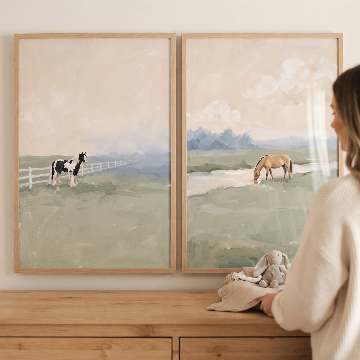 Ethereal muted meadow horse artwork set of 2 with a black and white horse and a tan horse in wood frames above a dresser.