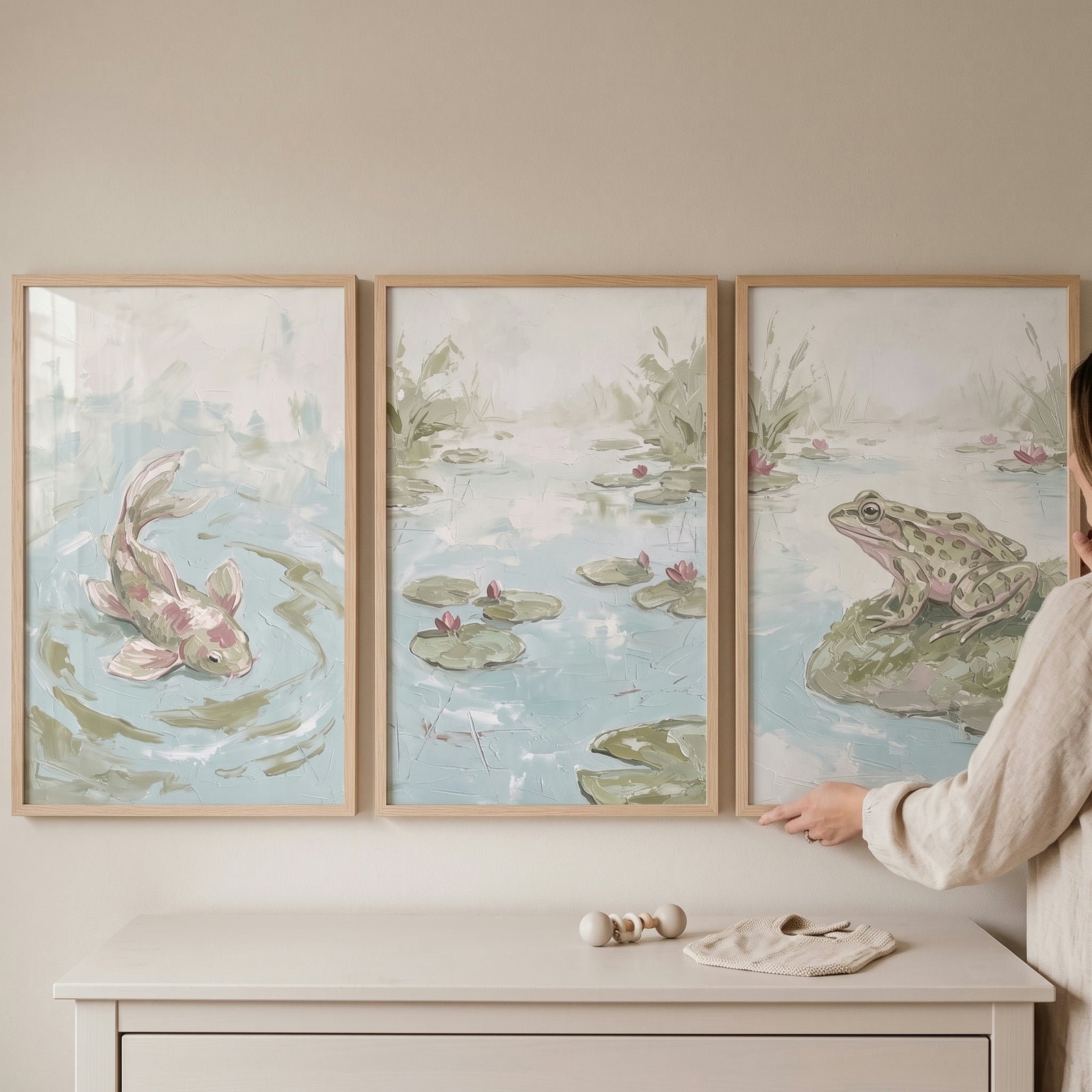 Ethereal muted pond wall art set of 3 featuring a koi, frog, and lily pads above a white dresser in a light green room.