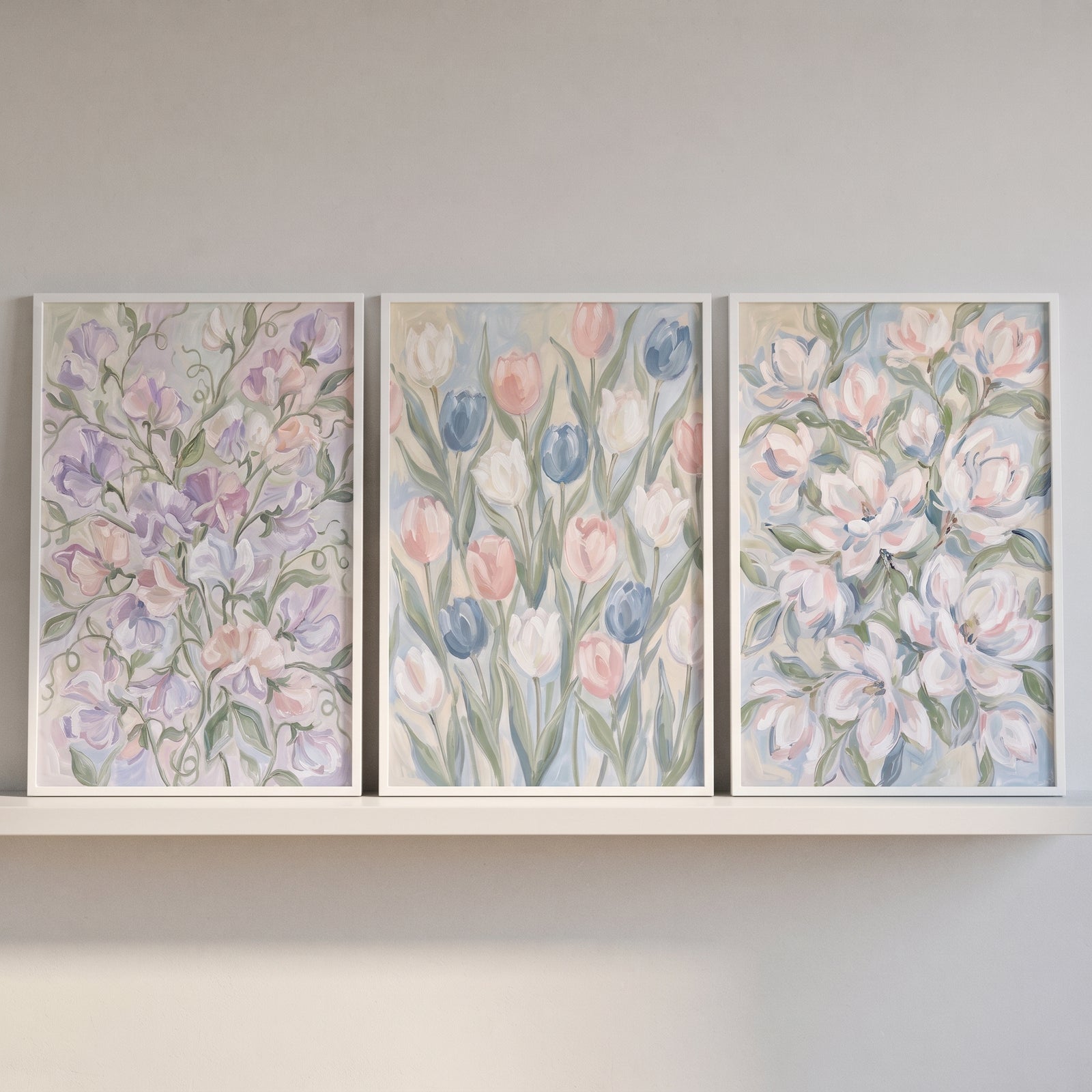 An ethereal pastel garden floral wall art set of 3 with soft floral designs sits on a white shelf against a neutral wall.