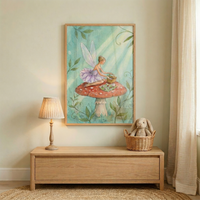 A framed vertical illustration hangs on a light-toned wall, depicting a whimsical scene of a winged sprite. The character, dressed in a soft purple tutu-style dress with delicate translucent wings, is seated on top of a large red toadstool with white spots. She appears to be having a small picnic, with a woven basket and a tiny tea set placed on the mushroom's surface. The background of the artwork is a soft teal color, accented by gentle green vines and rays of warm light filtering through.

