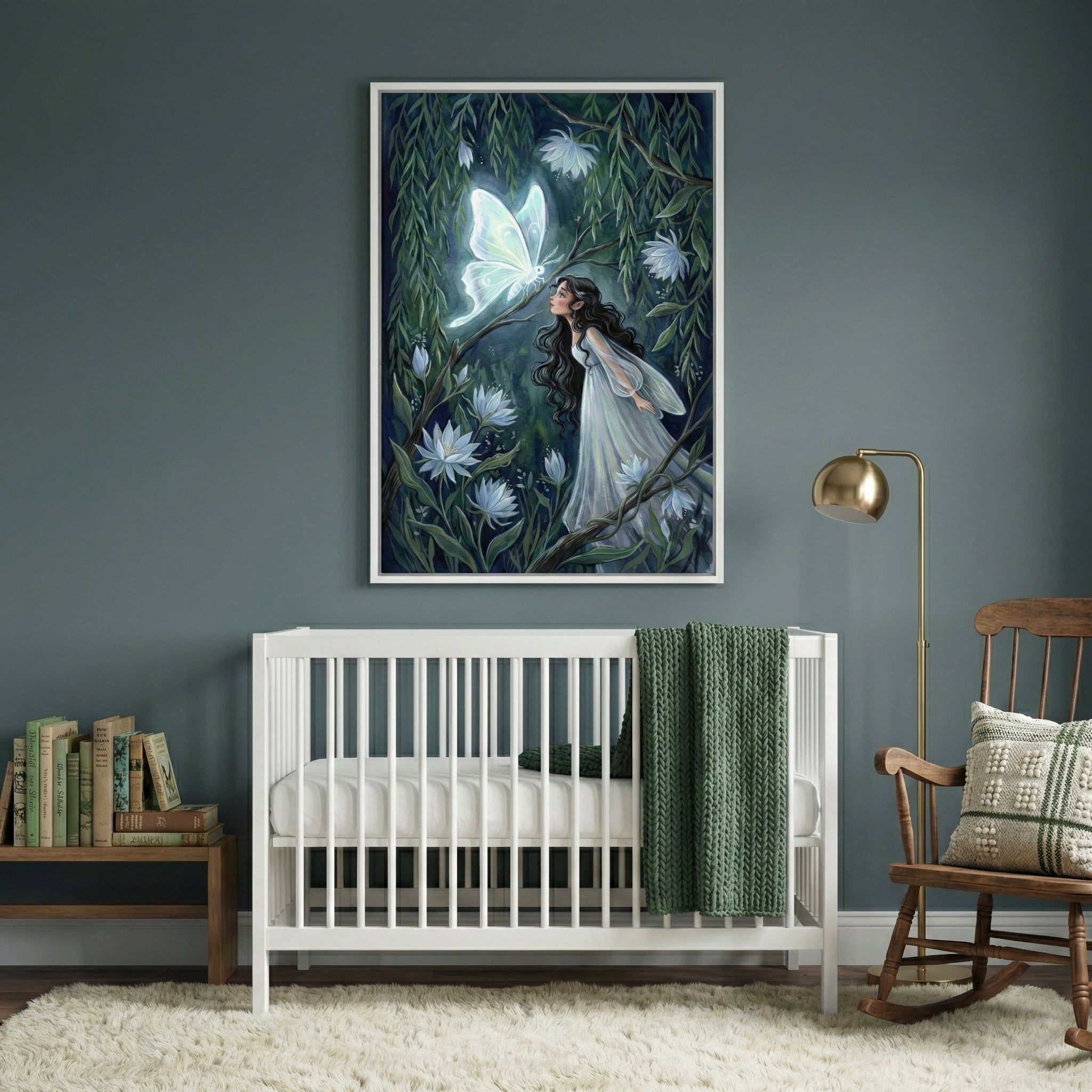 A serene nursery room with a white wooden crib centered against a dark teal wall. Above the crib hangs a large framed piece of art depicting a young woman in a flowing white dress in an enchanted forest, gazing at a large, luminescent white butterfly. To the right of the crib sits a wooden rocking chair with a patterned pillow and a gold floor lamp. To the left, a small wooden bench is topped with several books. A soft, textured white rug covers the floor, and a dark green knit blanket is draped over the ed