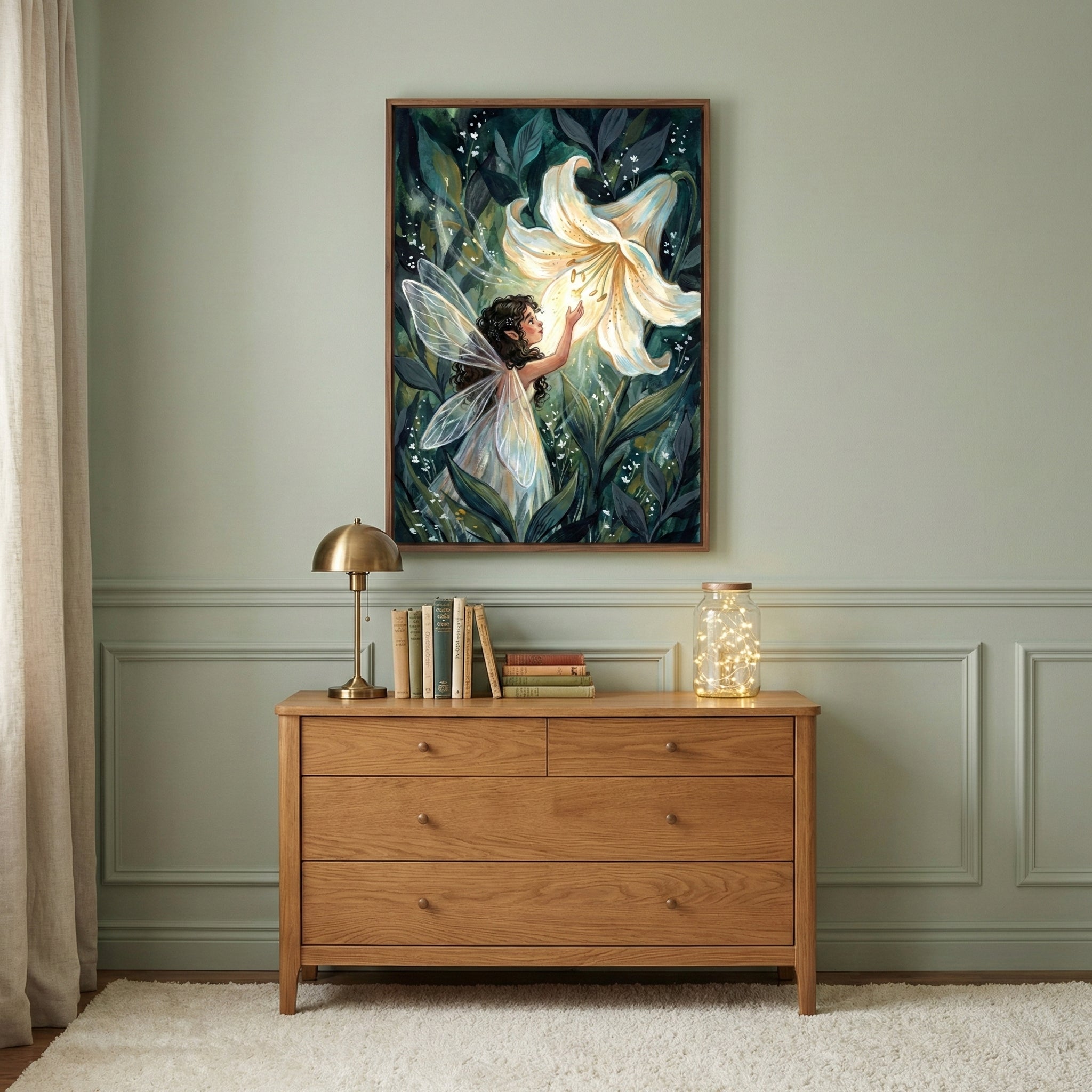 A framed illustration on a sage green wall above a wooden dresser. The art shows a small fairy with iridescent wings reaching for a large, glowing white lily amidst dark green foliage. On the dresser sits a golden dome lamp, a row of books, and a glass jar containing twinkling lights. A neutral-toned curtain hangs to the side, and a white textured rug is on the floor.