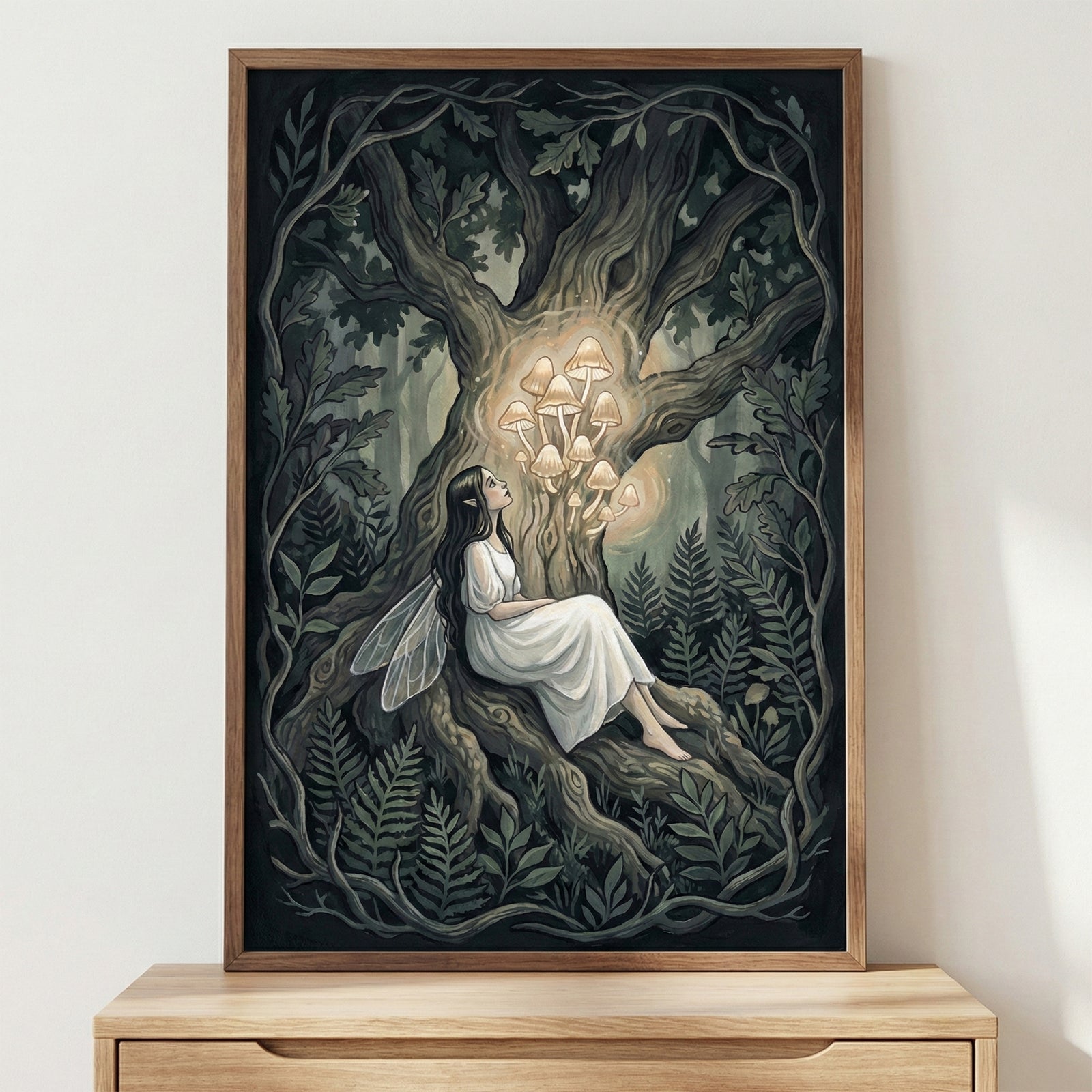 Framed painting of a fairy with translucent wings and a flowing white dress, sitting peacefully against the twisted roots of a large, ancient tree. She gazes upward at a glowing cluster of mushrooms sprouting from the tree trunk. The scene is set in a shadowy forest surrounded by ferns and dark foliage, creating a dreamy, magical woodland atmosphere. The artwork is displayed above a light wooden dresser in a softly lit room.