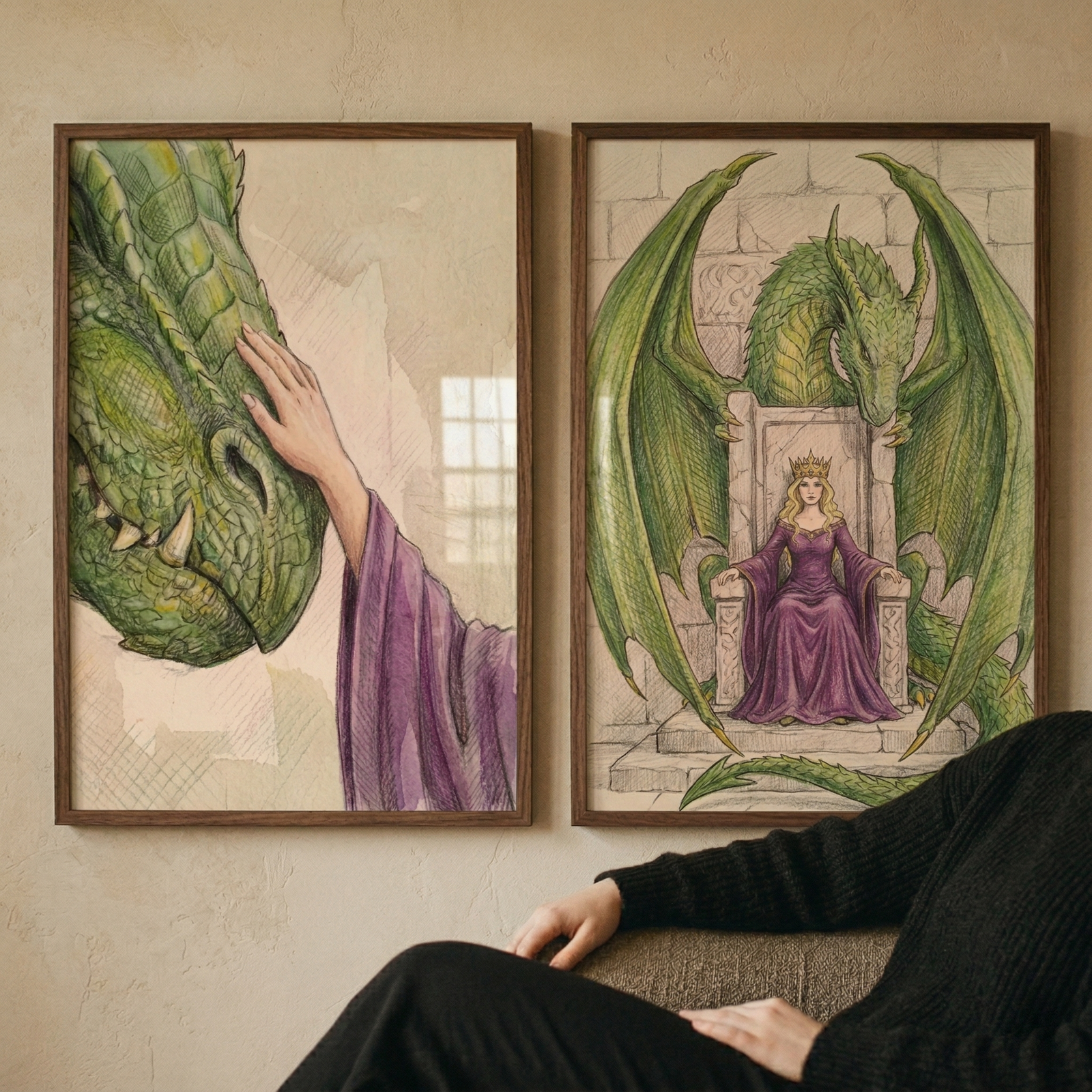 Two framed fantasy dragon prints hang side by side on a warm beige wall above a seated person in a black sweater. The left print shows a close view of a green dragon leaning into a gentle hand in a purple sleeve and the right print shows a crowned woman in a purple gown seated on a throne beneath a large green dragon with spread wings.