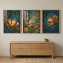A set of three framed vertical illustrations is mounted on a plain wall above a natural wood dresser. Each artwork depicts a different whimsical forest creature reading an illuminated book at night. From left to right, the scenes show a red fox nestled in a tree, a hedgehog cozy in a large leaf, and a squirrel on a pine branch. The illustrations feature deep blue tones and glowing dots like fireflies. A small wooden toy elephant sits on the four-drawer dresser below.