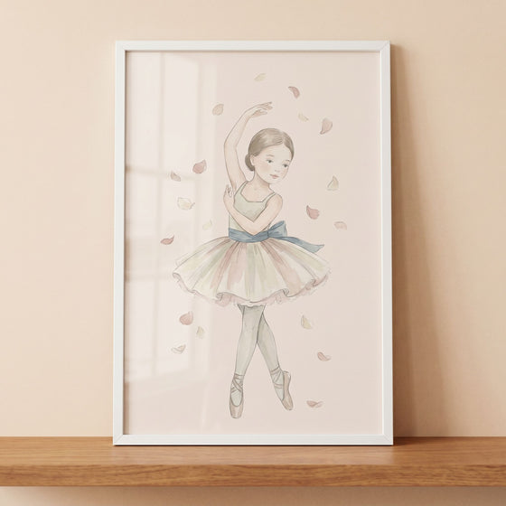 Falling petal watercolor ballerina wall art in a white frame on a wooden shelf shows a girl in a tutu among soft petals.
