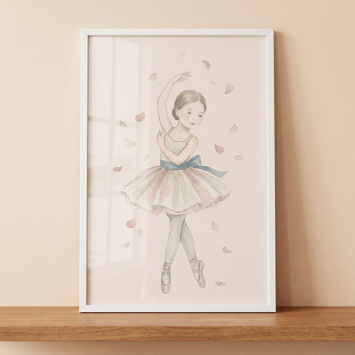 Falling petal watercolor ballerina wall art in a white frame on a wooden shelf shows a girl in a tutu among soft petals.