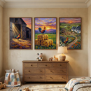 Three framed vertical farm-themed illustrations hang side-by-side on a cream wall above a wooden six-drawer dresser. The left piece shows a rooster in the doorway of a sunlit barn. The center piece features a rooster perched on hay bales in a field at sunset. The right piece portrays a rooster in a farm scene with a cottage and rolling hills. On the dresser are a plush cow, a small wooden animal toy, and a warm lamp. A basket with a patchwork blanket sits on the patterned rug below.