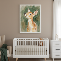 Modern nursery with a white crib, cream armchair, and white dresser. A large framed watercolor print of a fawn looking up against a green background hangs centered above the crib.