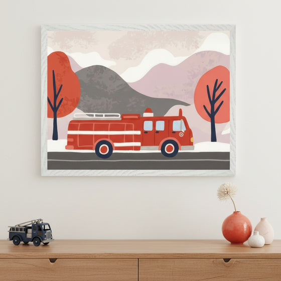 Modern kid's room with a light wood dresser. A framed illustration of a red fire truck in a stylized mountain landscape with red trees hangs centered above the dresser. A toy fire truck and decorative vases are on the dresser.