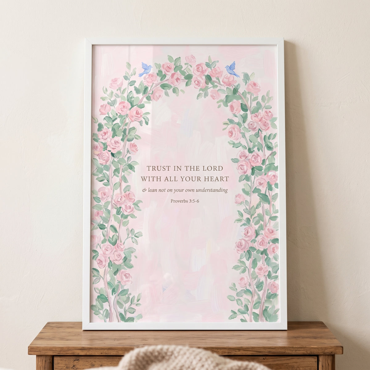 Floral arch proverbs verse bible wall art in a white frame with pink roses and small blue birds on a pink background.