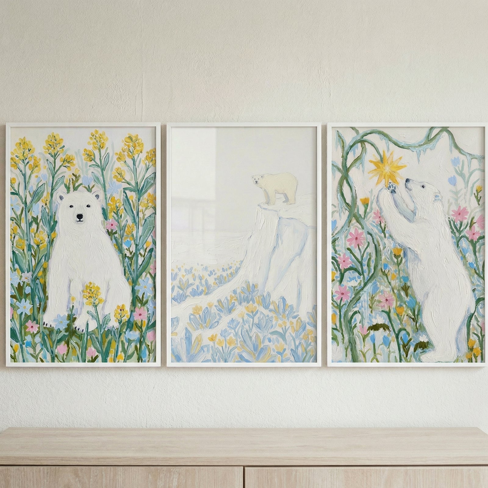 Three framed pastel paintings of white polar bears displayed side by side above a wooden surface. One bear sits among yellow flowers, one stands on a snowy cliff, and the third reaches toward a glowing star, creating a whimsical and storybook inspired art set.