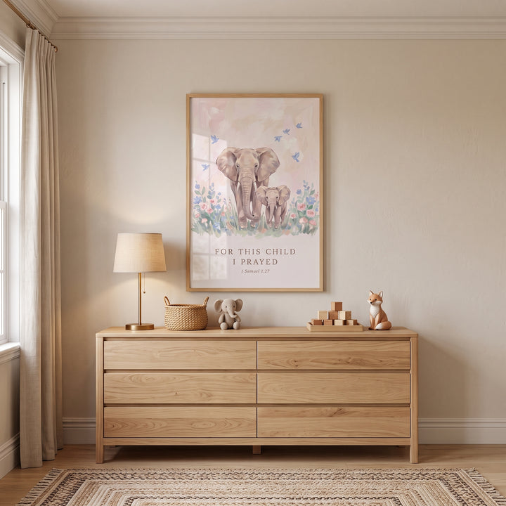 Floral mother baby elephant bible wall art hangs above a wooden dresser in a neutral nursery with a lamp and toys.