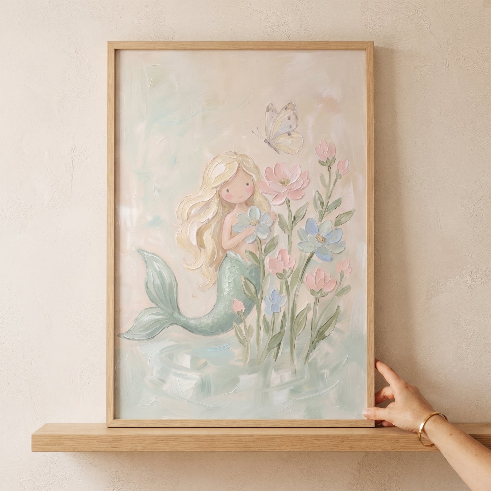 Floral pastel blonde mermaid wall art in a wooden frame shows a mermaid with a green tail, pink flowers, and a butterfly.