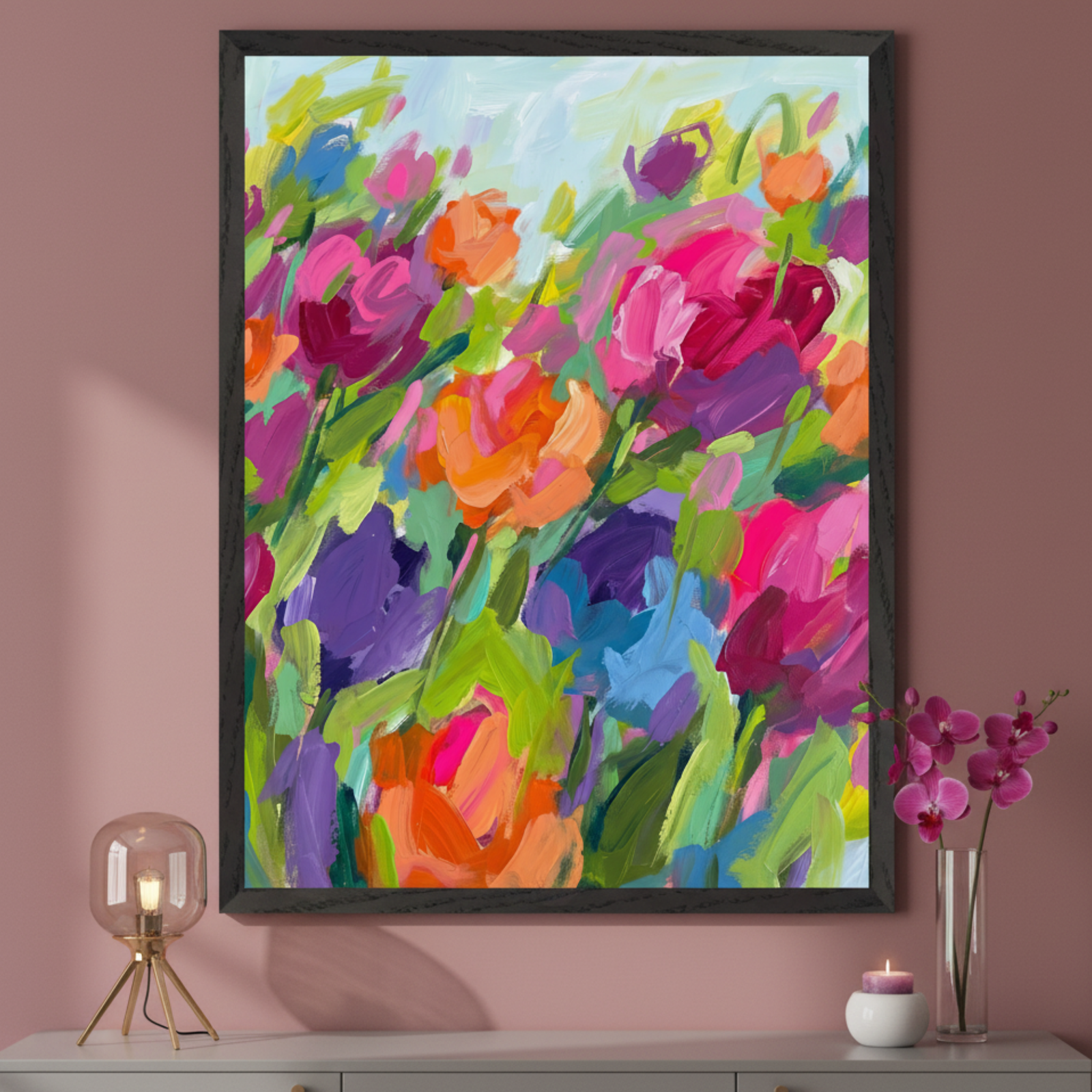 Modern room with a gray console table. A large framed abstract floral painting, featuring vibrant pink, orange, purple, blue, and green thick brushstrokes, is centered above the table. A lamp and a vase of fuchsia orchids are on the console.