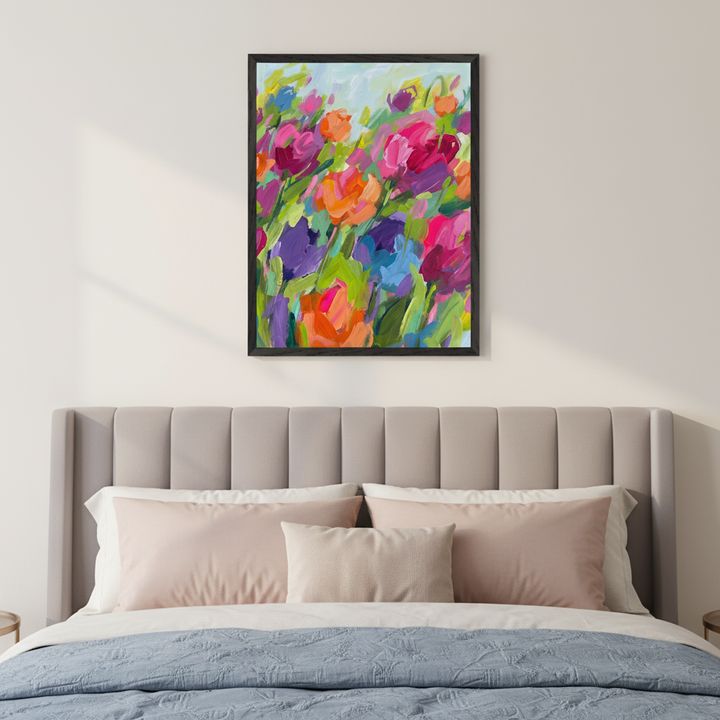 Modern bedroom with a light gray upholstered bed. A framed abstract floral painting with vibrant pink, orange, purple, blue, and green brushstrokes hangs centered above the headboard.