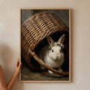 Framed flower crown white rabbit wall art features a bunny inside a rustic, tipped-over wicker basket.
