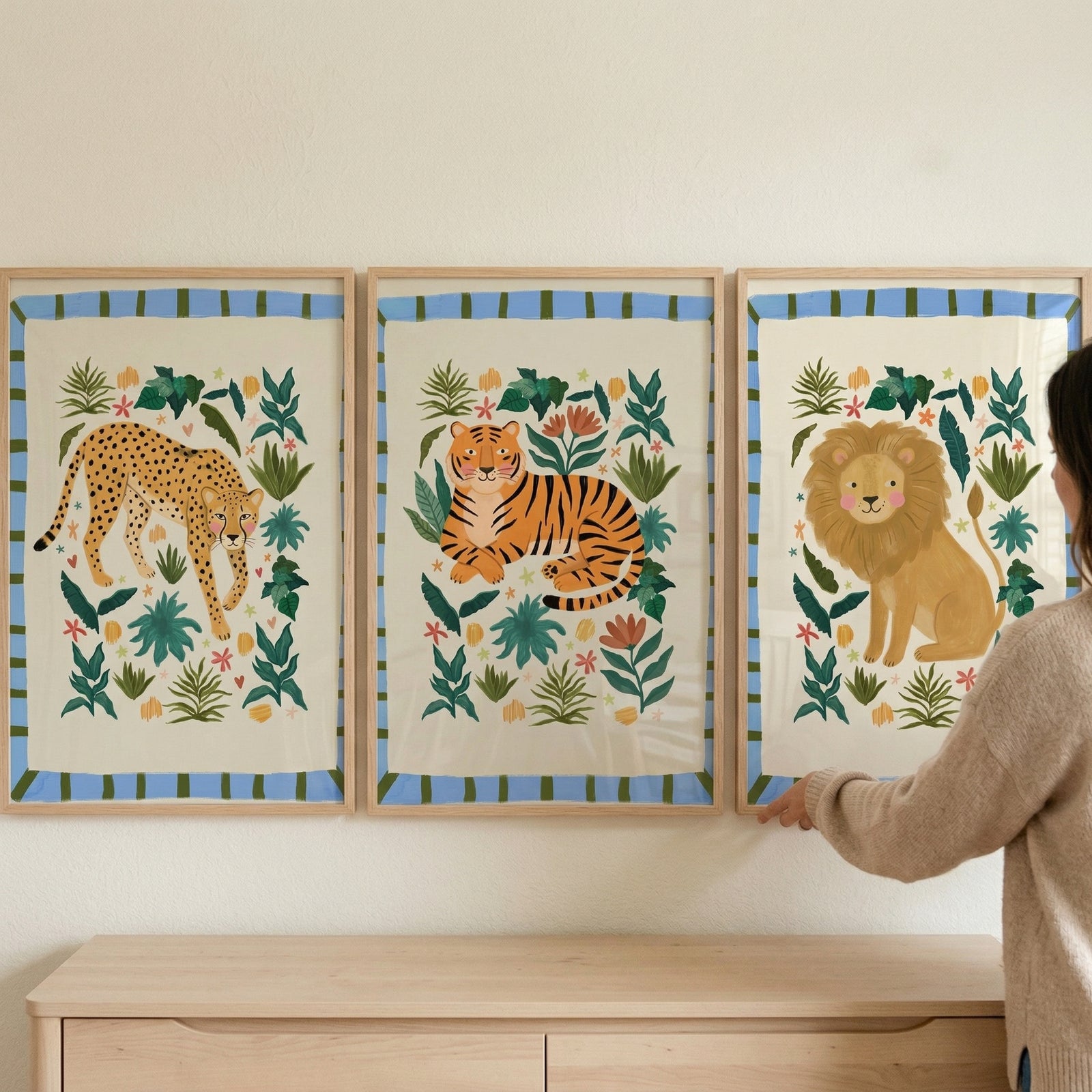 Folk style botanical cat wall art set of 3 featuring a cheetah, tiger, and lion hangs above a light wood dresser.
