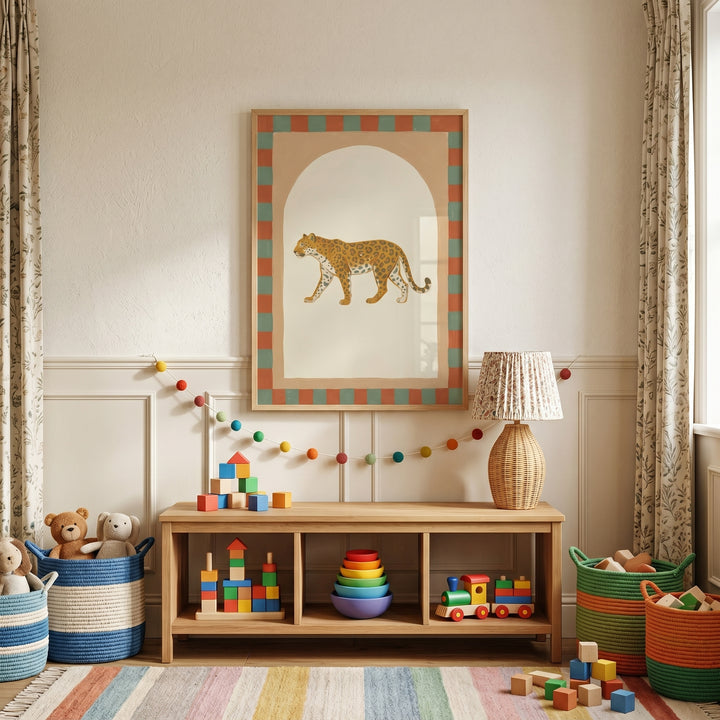 Toys sit on a wood shelf below folk style walking leopard wall art in a room with a striped rug and pom-pom garland.