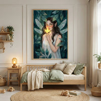 A serene bedroom interior featuring a large framed illustration centered on a paneled wall above a light wooden daybed. The artwork depicts a dark-haired ethereal figure with translucent wings, holding a small glowing flower against a background of lush green leaves. The daybed is adorned with soft green and neutral-toned pillows and blankets. To the left, a small wooden side table holds a warm lamp, and a wall shelf holds books and a hanging plant. A circular natural fiber rug lies on the floor with wooden