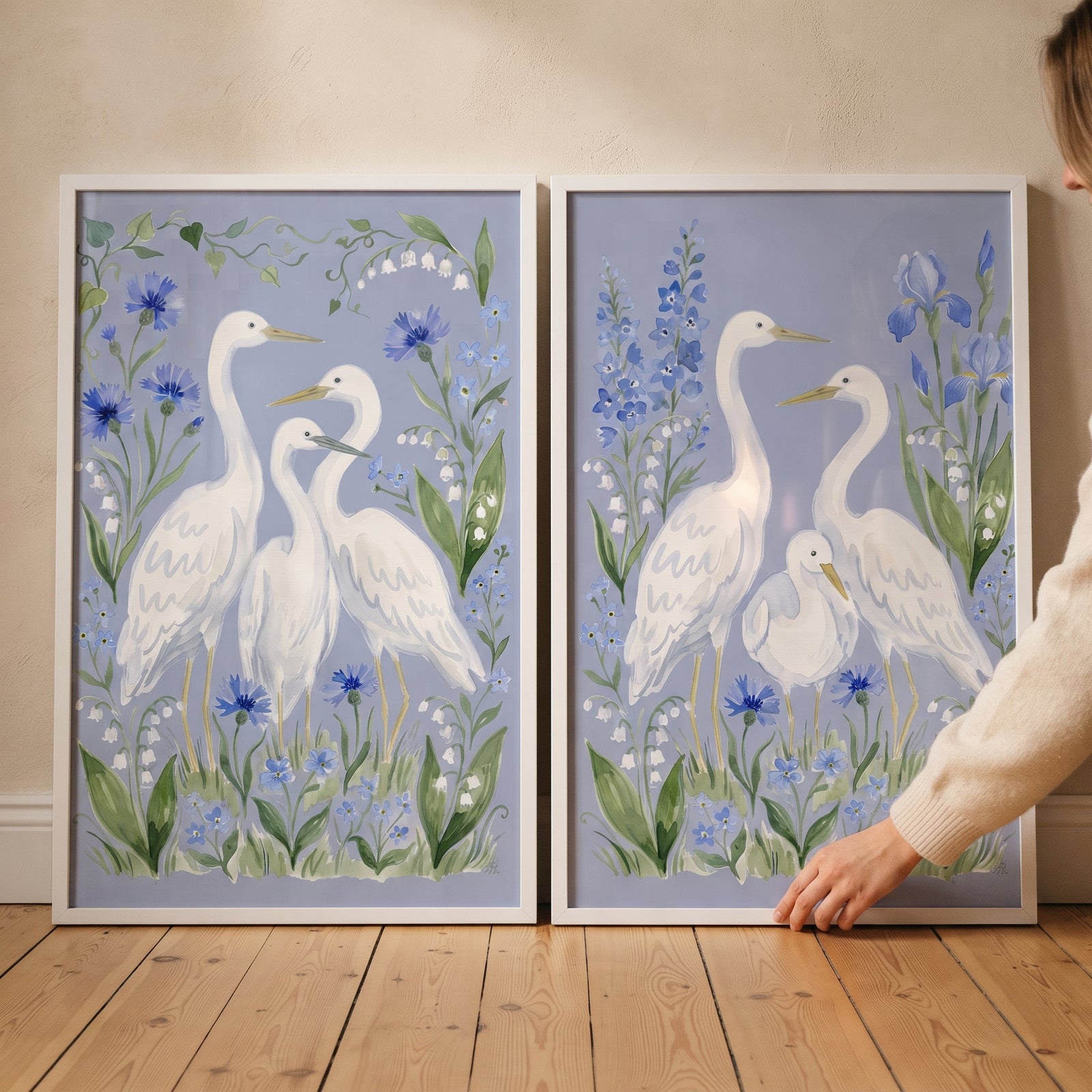 Forget me not heron bird wall art set of 2 featuring white herons and blue wildflowers in matching white frames.