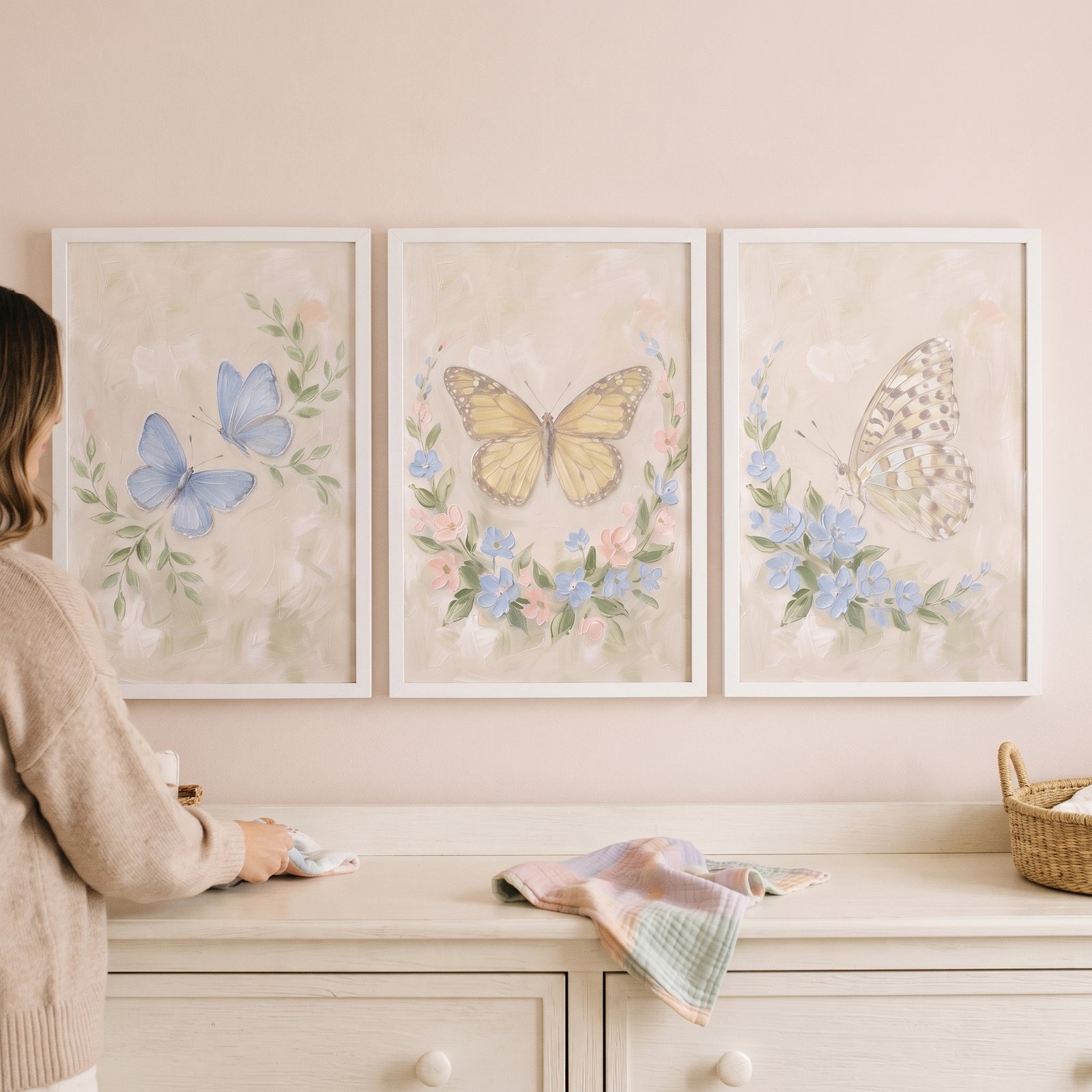 french cottage garden butterfly wall art set of 3 hangs above a dresser in a soft pastel room with a woman and wicker basket.