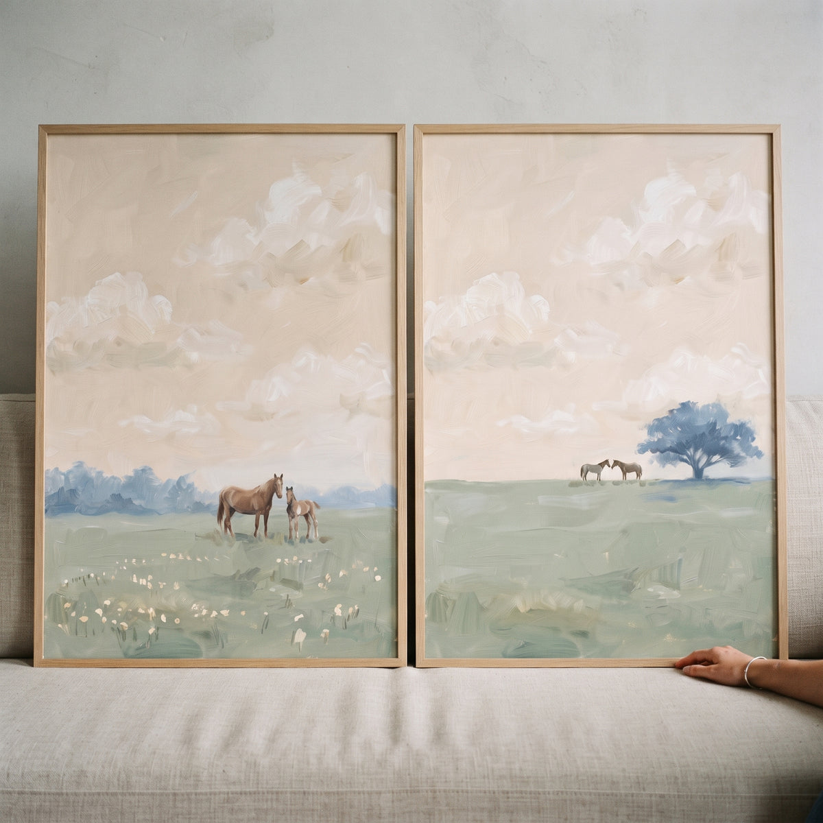 French countryside meadow horse wall art set of 2 shows horses in soft green fields beneath a neutral, cloudy sky.