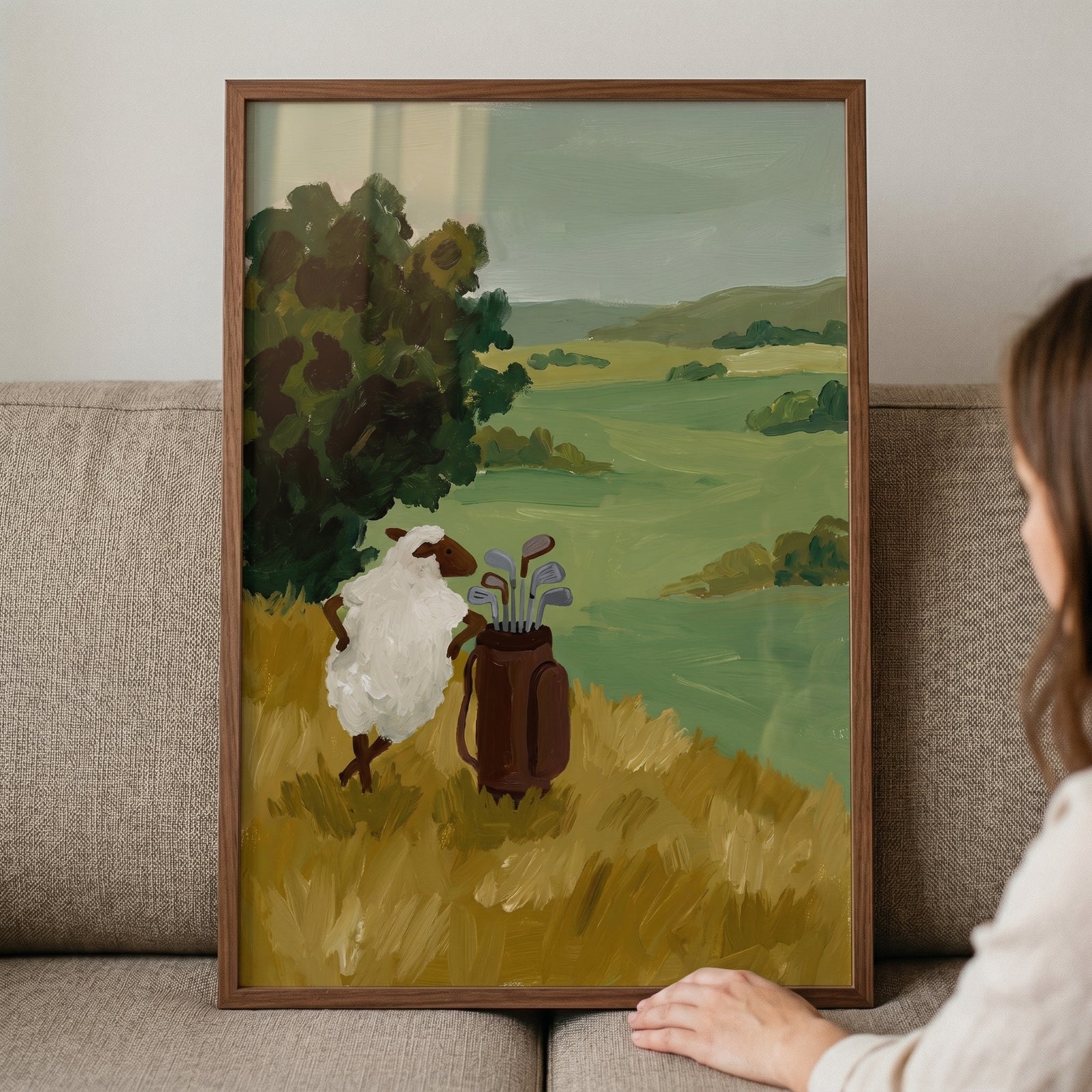 Framed funny golf bag sheep wall art shows a white sheep next to a brown golf bag on a rolling green hillside.