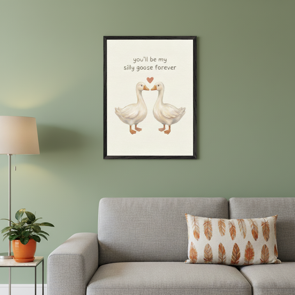 Modern living room with a gray sofa against a green wall. A black-framed print on a cream background, featuring two white illustrative geese, a red heart, and text "you'll be my silly goose forever", hangs above the right side of the sofa.