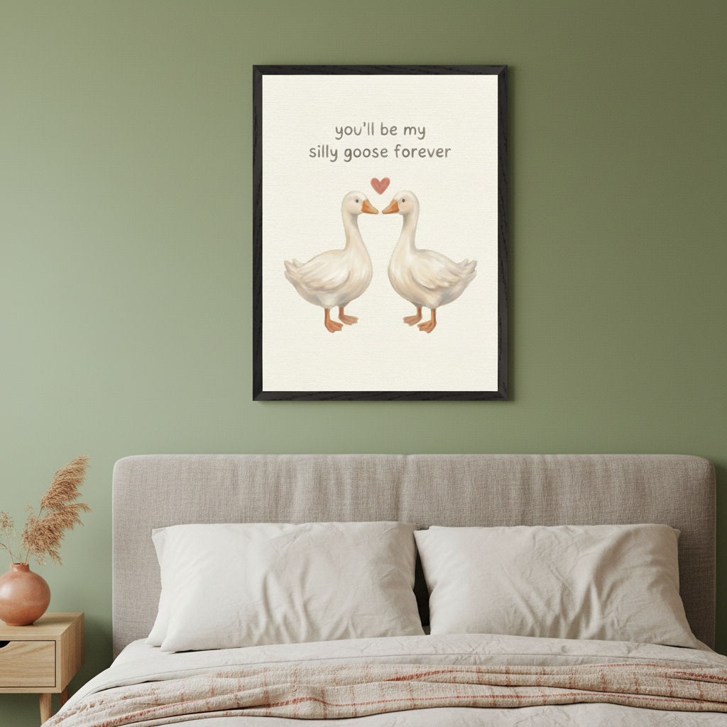 Modern bedroom with a bed, grey headboard, and a wood nightstand. A black-framed illustration of two white geese with a heart and text "you'll be my silly goose forever" hangs above the bed.