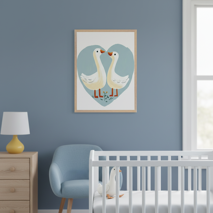 Modern nursery with a white crib, light wood dresser, and blue accent chair. On the blue wall, a framed print of two white geese facing each other within a light blue heart hangs above the chair, left of the window and crib. The art is in a whimsical illustration style.
