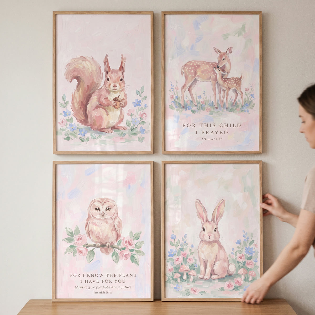Gentle pink woodland animals wall art set of 4 features framed illustrations of a squirrel, deer, owl, and rabbit.