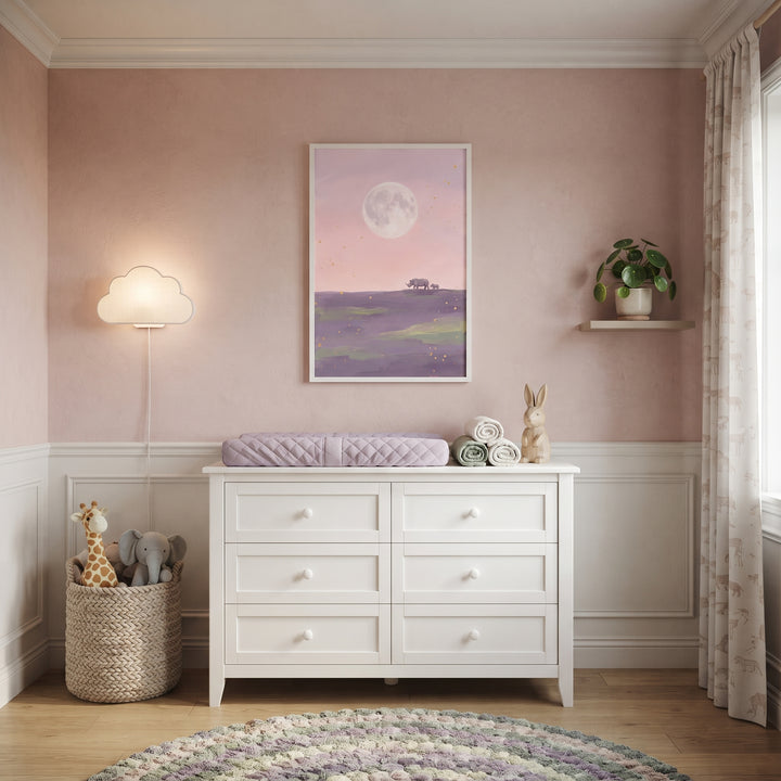 Nursery with a white dresser, cloud lamp, round rug, and giant moon walking rhino animal wall art on a pink wall.