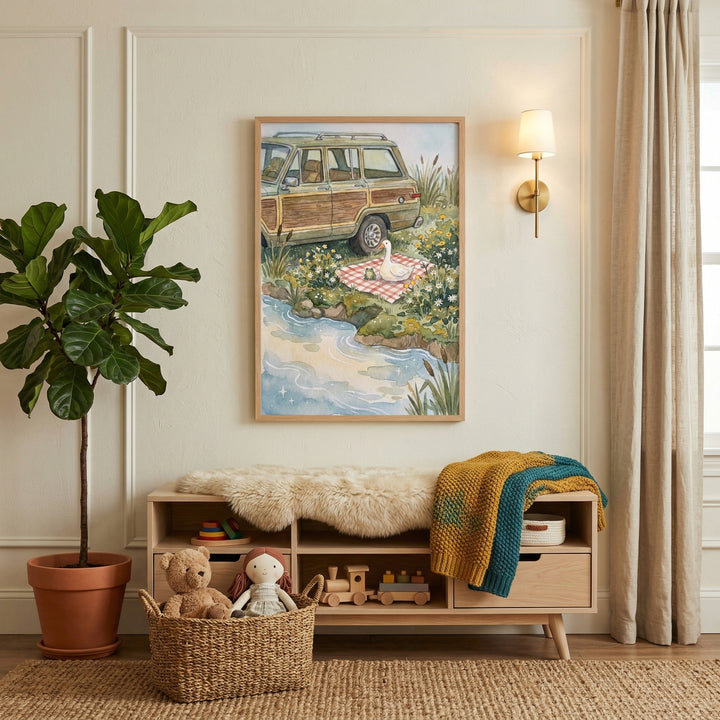 This cozy interior scene features a neutral-toned room, likely a nursery or child's play area, with an inviting and whimsical feel. The focal point is a large framed illustration hanging on an off-white wall with elegant decorative molding. The artwork depicts a vintage wood-paneled station wagon parked near a winding blue river. 