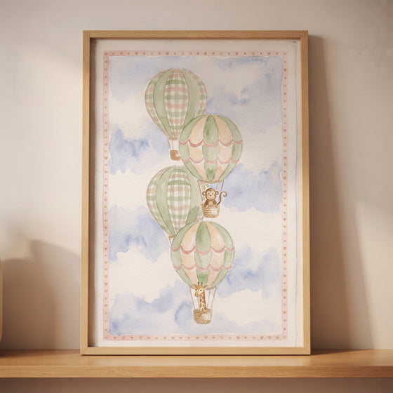 Watercolor gingham hot air balloon wall art with a monkey and giraffe in a blue sky, in a wooden frame on a shelf.