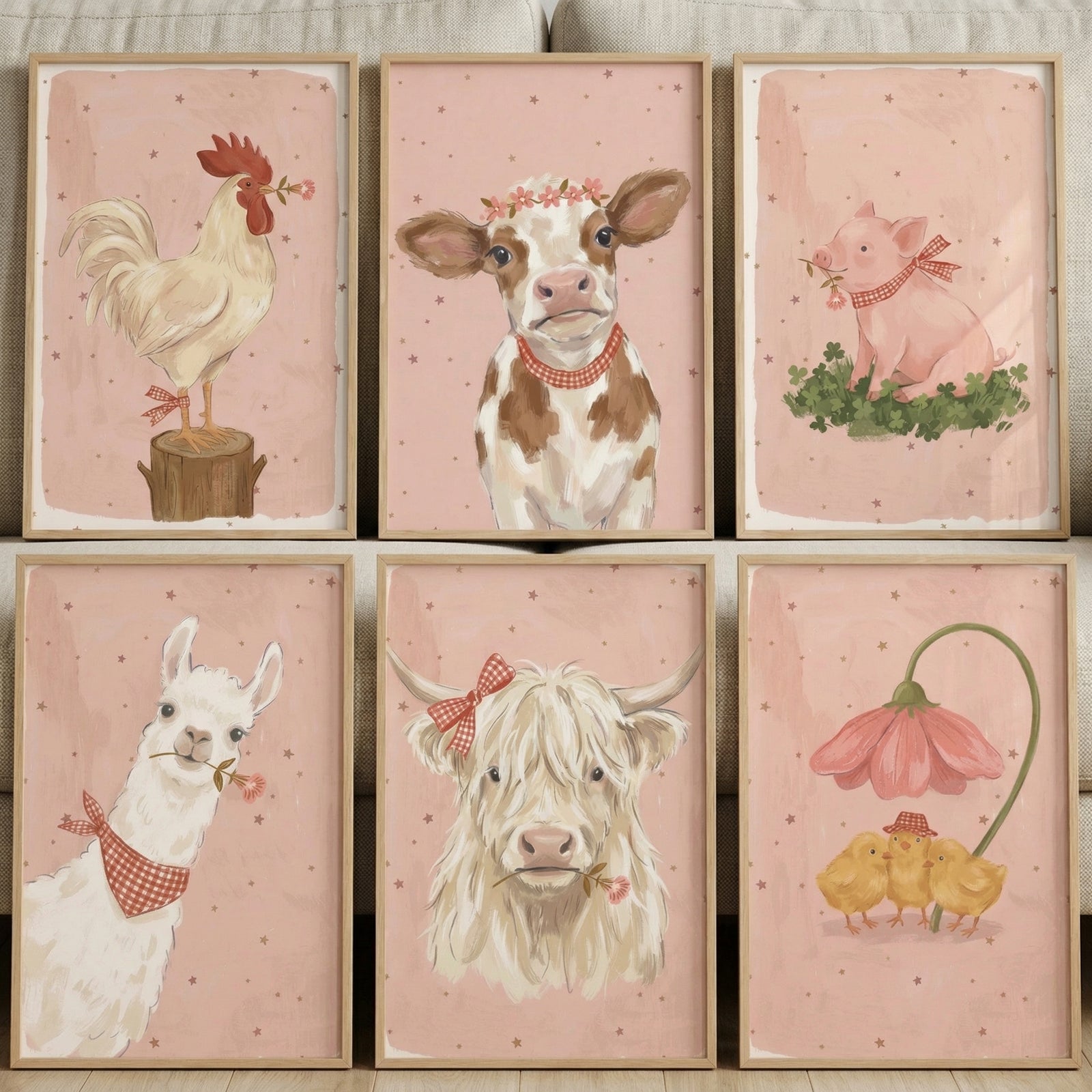 Six framed pastel farm animal illustrations arranged in two rows show a rooster, calf, pig, llama, highland cow, and three chicks under a flower, each with red checkered accessories and small floral details. The soft pink star patterned backgrounds and coordinated style create a cohesive and charming nursery wall art collection.