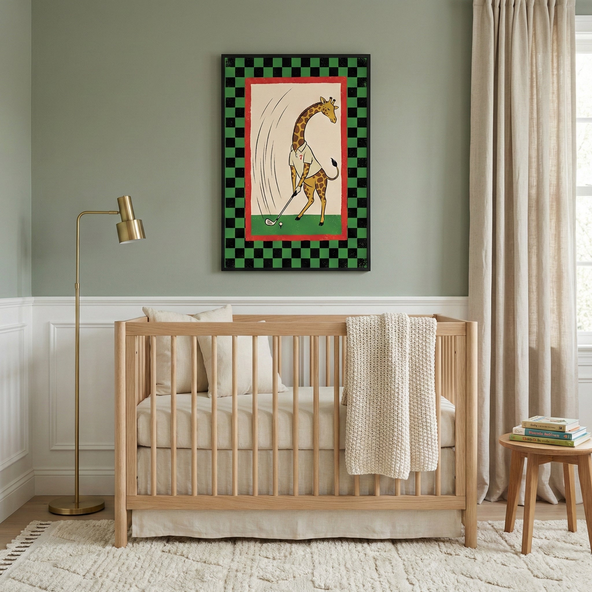 A neutral-toned nursery with sage green walls and white wainscoting. A light wood crib with cream-colored bedding and a white knit blanket is centered against the wall. To the left is a sleek gold floor lamp. Above the crib, a framed piece of art depicts a whimsical cartoon giraffe in a white shirt playing golf, set against a backdrop of a green field with a red border and a green and black checkered outer frame. 