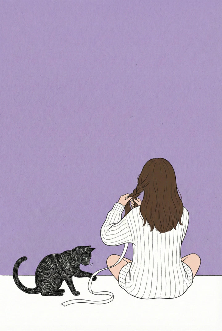 A girl in a striped sweater sits on the floor braiding her hair while a black cat plays with a loose ribbon. The scene is minimal with a lavender wall and white floor.