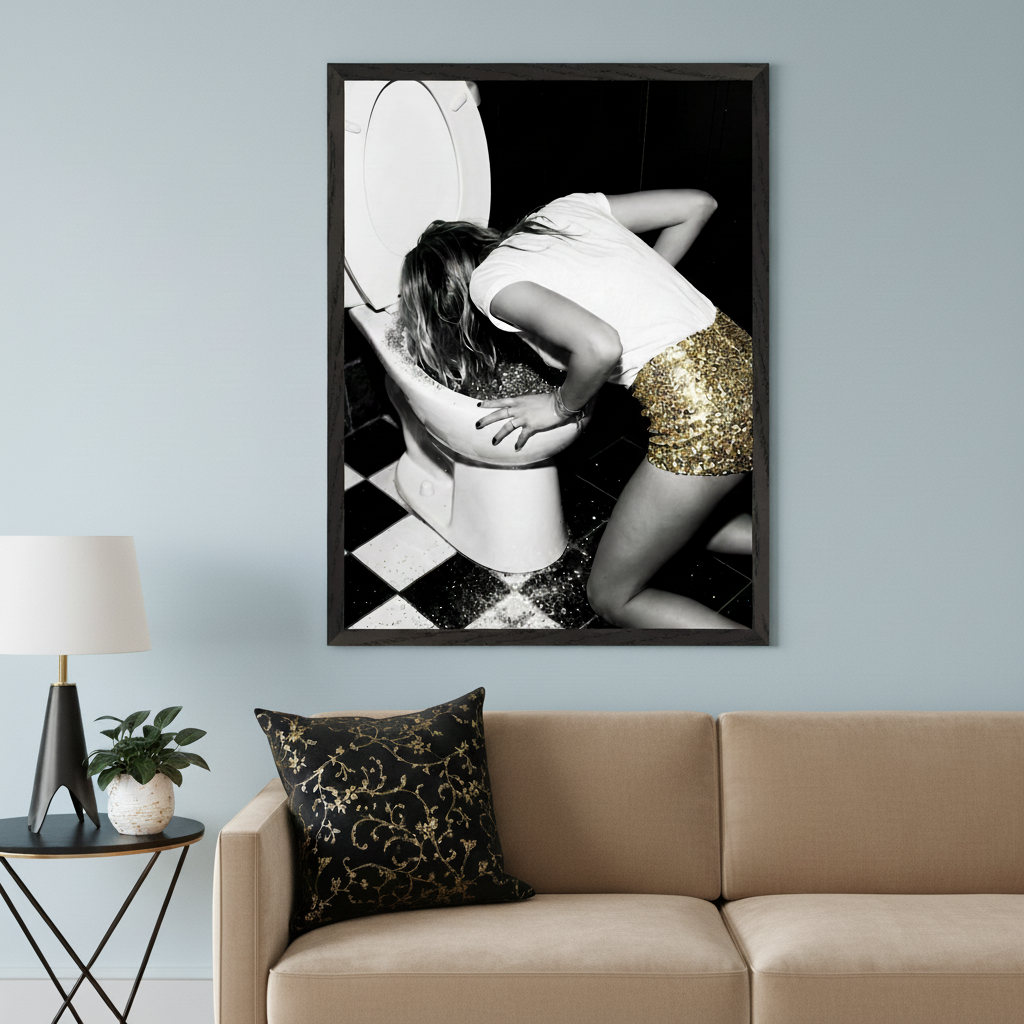 Modern living room with a beige sofa and black side table. Above the sofa, a large framed black and white photo of a woman in a gold sequin skirt leaning over a toilet, with glitter on the floor.